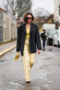 mujer con blazer negra y pantalon y top amarillo